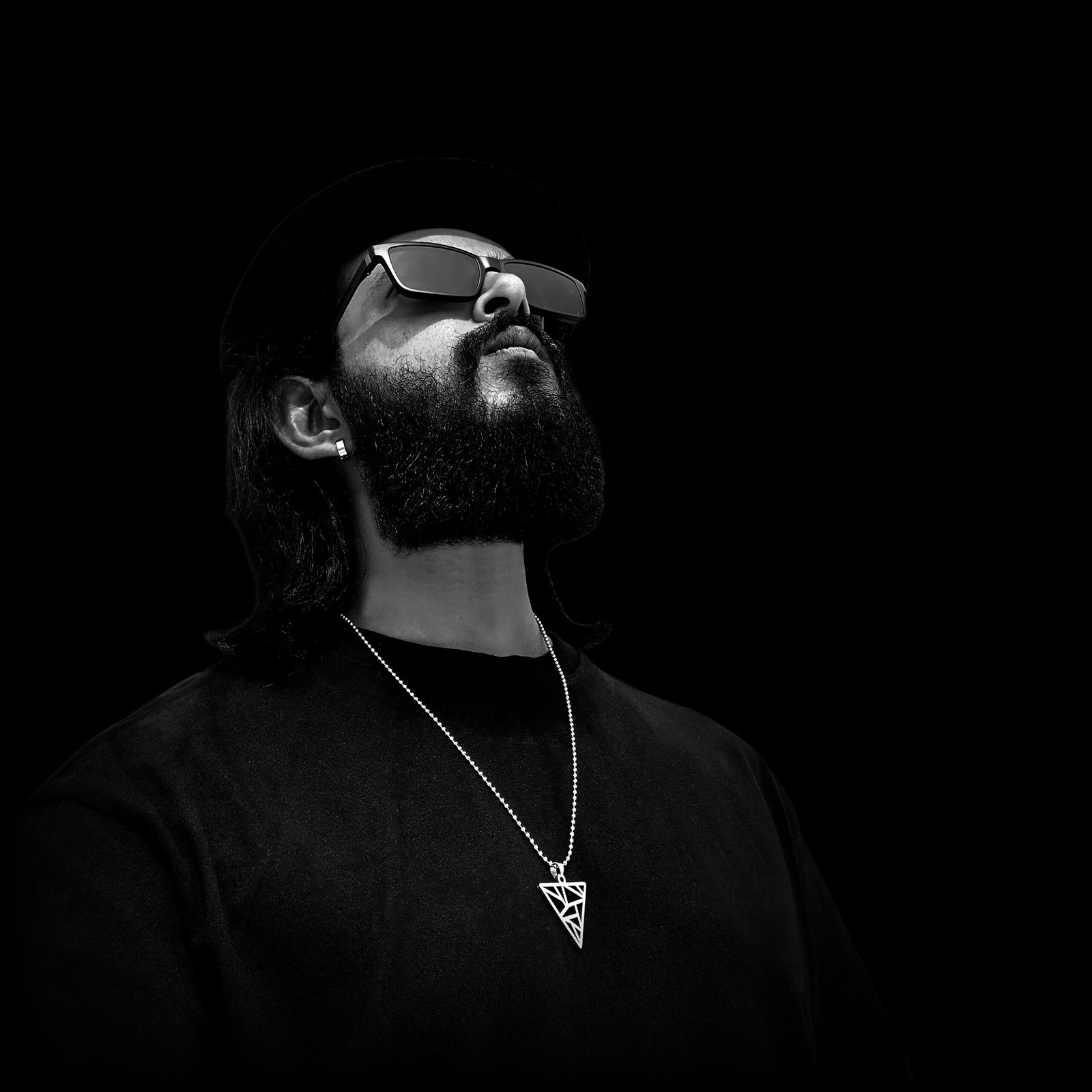 A man with a beard wearing sunglasses and a necklace