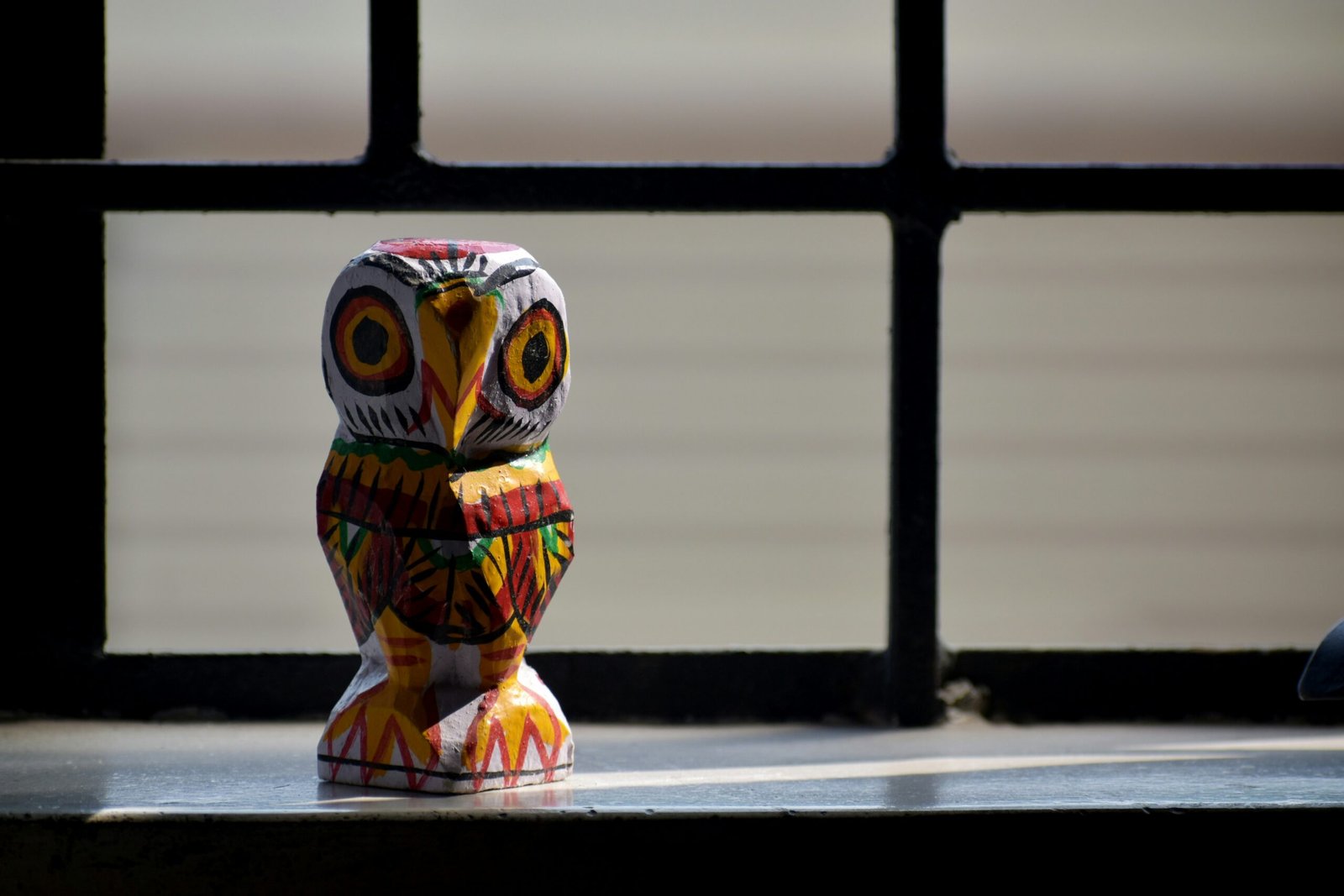 an owl figurine sitting on a window sill